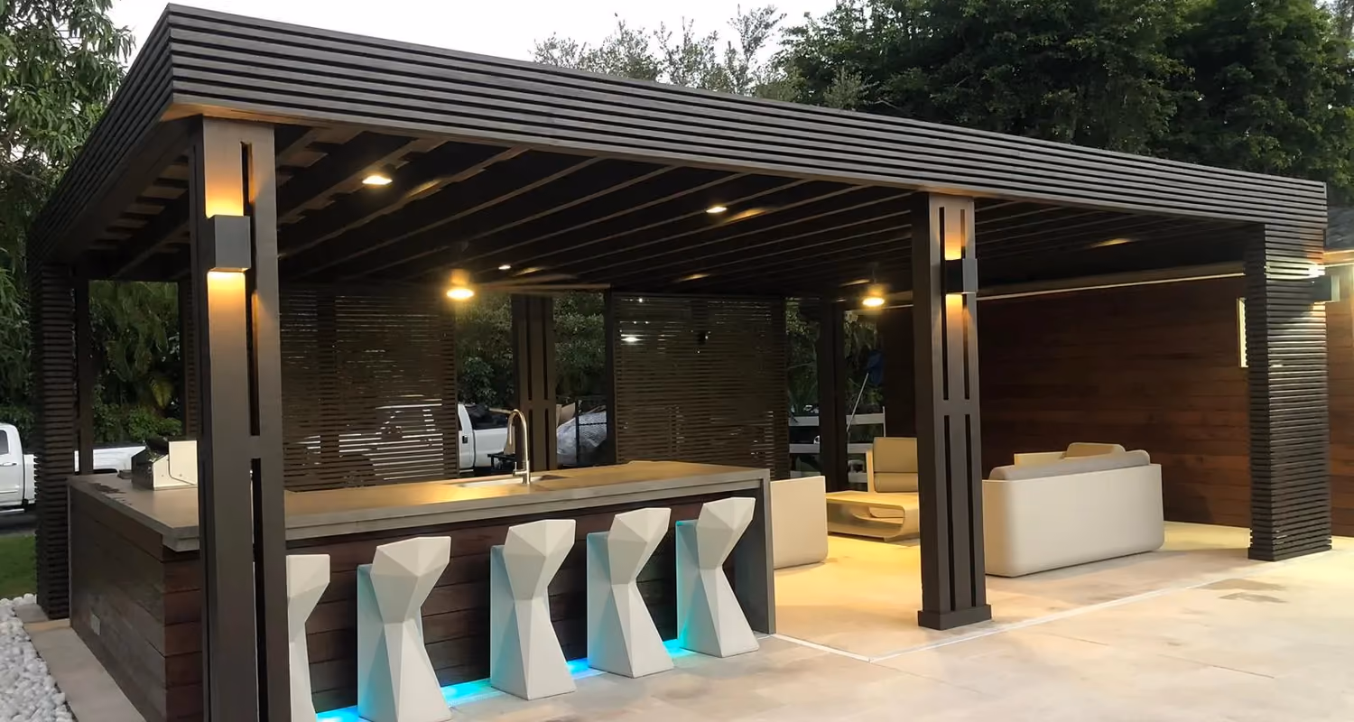 Dark wood pavilion with outdoor bar, sculptural stools, LED toe-kick lights and lounge at dusk.